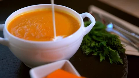 Chef adding cream garnish to pumpkin soup Video stock 105864887