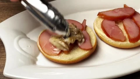 Chef adding creamy oyster mushrooms on smoked deli meat slices for a burger prep Stock Footage 325032256