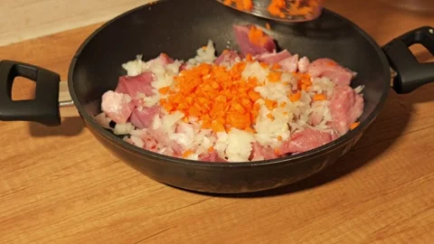 Chef adding diced carrots to meat stew preparation Video stock 342758749