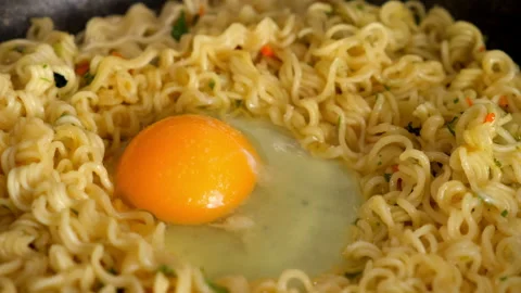 Chef adding egg to instant noodles cooking in frying pan adding salt. Stock Footage 311892077