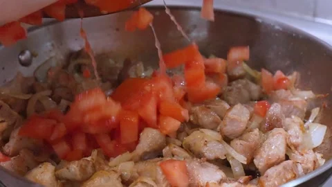 Chef adding fresh diced tomatoes to sizzling meat Stock Footage 337169283