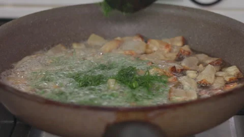 Chef Adding Fresh Dill to Crispy Golden Pork Cracklings in a Frying Pan Stock Footage 339658810