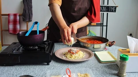 Chef adding freshly grated cheese onto spaghetti Bolognese to garnish finished Stock Footage 345379869