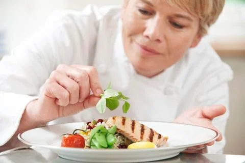 Chef Adding Garnish To Meal In Restaurant Kitchen Stock Photos