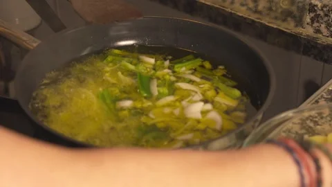 Chef adding green pepper and onion to hot oil in a frying pan Vídeos de archivo 331314032