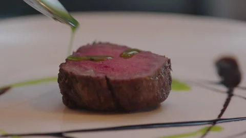 Chef adding green sauce over a steak Stock Footage 283005852