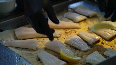 Chef adding lemon slices to fish fillets during cooking. Stock Footage 294979742
