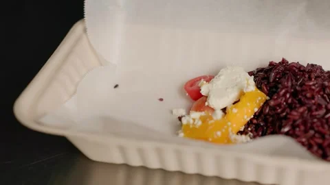 Chef adding mango-feta salad next to red rice in compostable takeout box Stock Footage 312814067