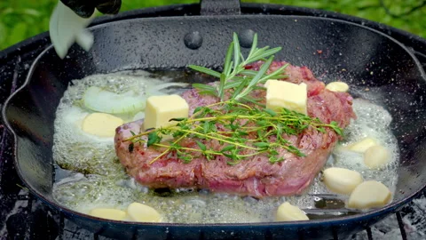 A chef adding onions to a pan where beef steak is being cooked. Stock Footage 315904579