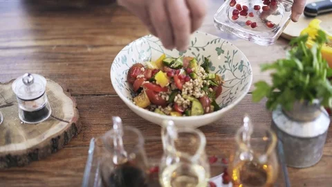Chef adding a pomegranate, a sauce and an olive oil to a vegetable salad 스톡 동영상 76591387