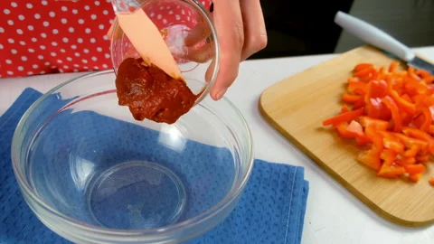 Chef adding rich tomato paste into glass bowl while preparing fresh ingredients. Stock Footage 312399940