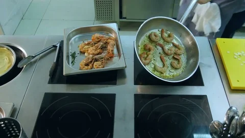 Chef adding salt and garlic to shrimps frying in a pan Stock Footage 72325609