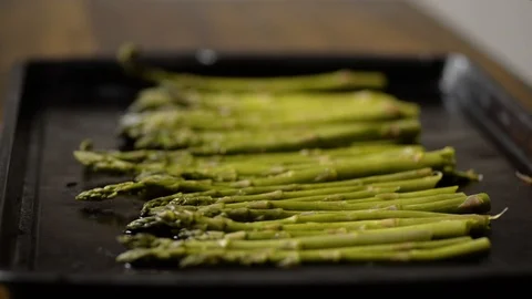Chef adding salt to fresh asparagus on a baking sheet Stock Footage 116787283