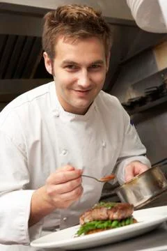 Chef Adding Sauce To Dish In Restaurant Kitchen Stock Photos