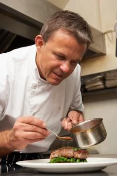 Chef Adding Sauce To Dish In Restaurant Kitchen Stock Photos