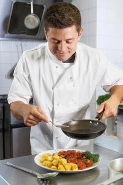 Chef Adding Sauce To Dish In Restaurant Kitchen Stock Photos