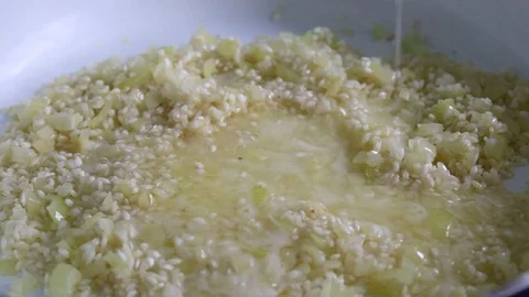 Chef adding sauce to the risotto rice frying on white ceramic pan Video stock 78734254