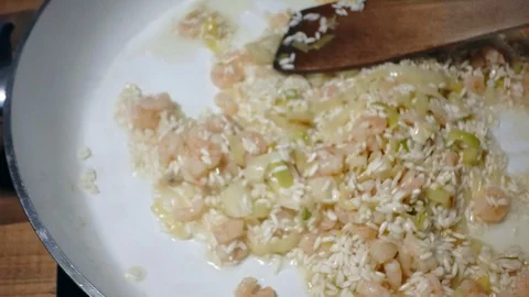 Chef adding sauce to tasty risotto rice with prawns frying on white ceramic pan Stock Footage 86973594