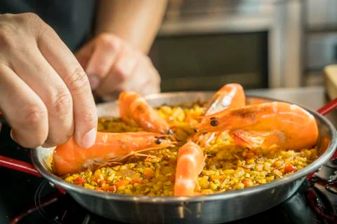 Chef is adding seafood to paella, close up Фото
