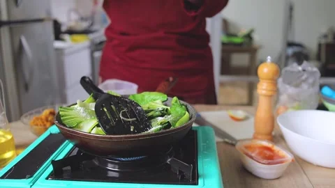 Chef adding seasoning and salt onto bok choy vegetables cooking in frying pan Stockbeeldmateriaal 341485820
