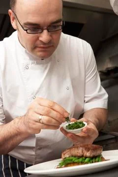 Chef Adding Seasoning To Dish In Restaurant Kitchen Stock Photos