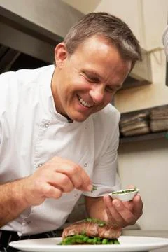 Chef Adding Seasoning To Dish In Restaurant Kitchen Stock Photos