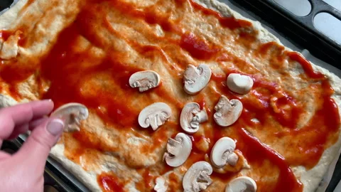Chef adding sliced mushrooms to pizza dough with tomato sauce Stock Footage 311320448