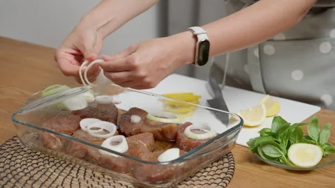 A chef adding sliced onions to raw tuna steaks before baking in the oven. Vídeos de archivo 315689807