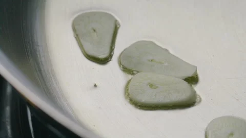Chef Adding Slices of Garlic to Sizzling Oil in Frying Pan Stock Footage 288786187