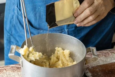 A chef adding spice to mashed potato filling for dumplings in a rustic meta.. Stock Photos