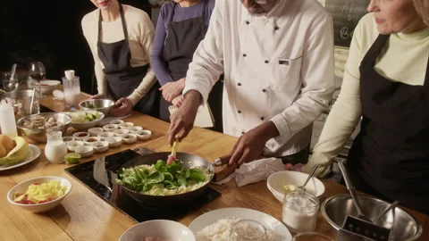 Chef Adding Spinach to Rice in Pan During Group Cooking master class Stock Footage 332574019