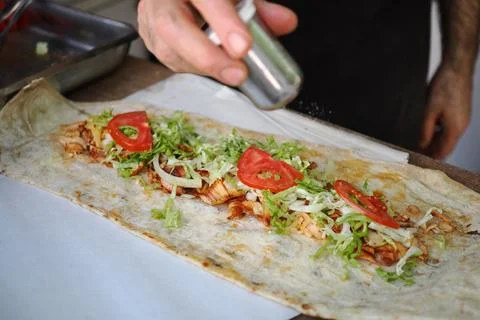 Chef adding toppings to a wrap in a busy street food market in the afternoon Stock Photos