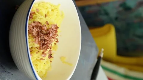 The chef adds bacon pieces to the grated potatoes in the bowl. Vertical video. Stock Footage 305154699