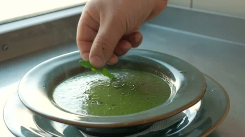 Chef adds basil to a spinach puree soup Stock Footage 92939534