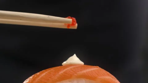 Chef adds caviar to the sushi roll with salmon and rice Stock Footage 143592939