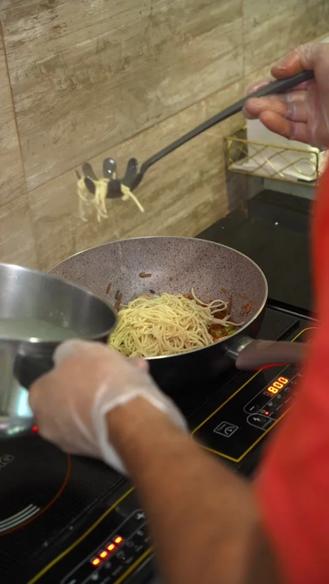 Chef adds cooked noodles to a wok with chicken and vegetables Stock Footage 346717935