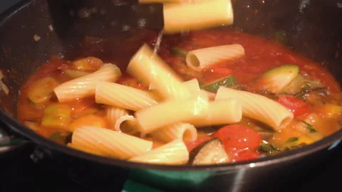 The chef adds pasta to the frying pan to the vegetables Stock Footage 158020522