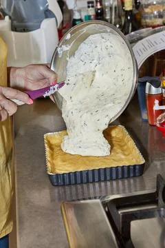 Chef adds pie dressing to the pie dough in a metal mold Stock Photos