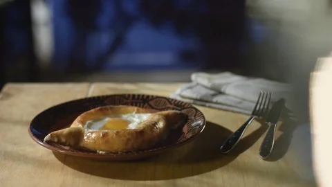 Chef adds a piece of butter to cooked khachapuri, served on the dining table Stock Footage 76856283
