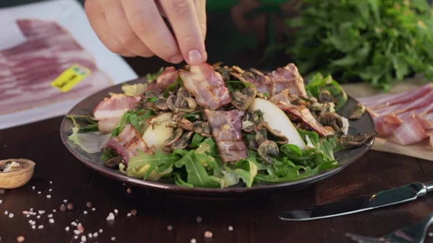 Chef adds roasted slice of bacon to the vegetable salad Stock Footage 143776557