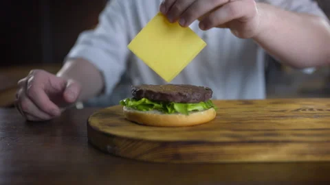Chef adds sliced cheddar cheese to the burger Video stock 143776676