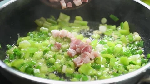 The chef adds sliced meat to the pan with green peppers, onions and garlic. Stock Footage 210717379