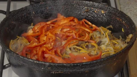Chef adds sliced red peppers to the fried vegetables in the frying pan Stock Footage 304686084