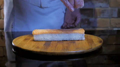 Chef adds sugar or salt on the top of sushi maki. Rice rolls preparing process Stock Footage 132184533
