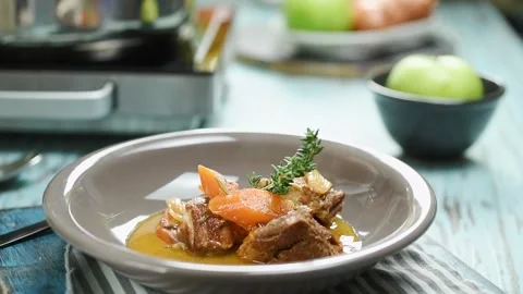 The chef adds thyme to the braised pork shoulder, served on the plate. Stock Footage 244387075