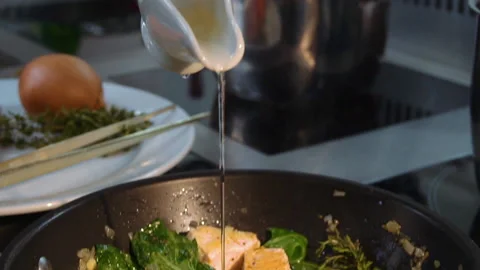 The chef adds wine to the pan with salmon and vegetables Stock Footage 158020227