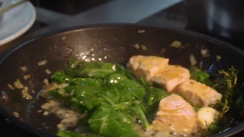 The chef adds wine to the pan with salmon and vegetables Stock Footage 158020245