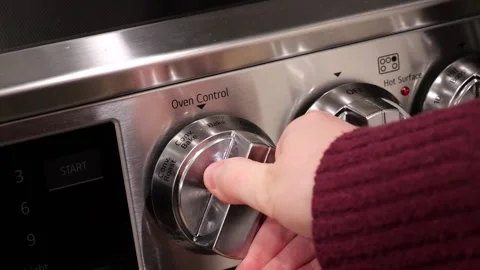 Chef adjusting oven temperature control knob on stainless steel stove Stock Footage 305808240