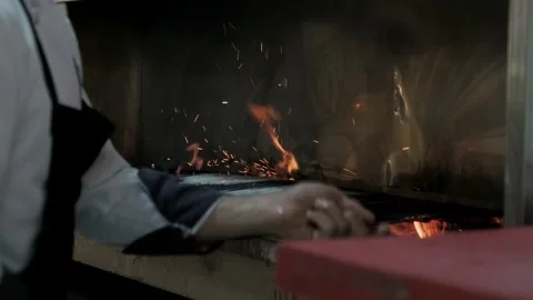 The chef adjusts the fire and embers of the grill. Fire and grill footage. Stock Footage 233066584