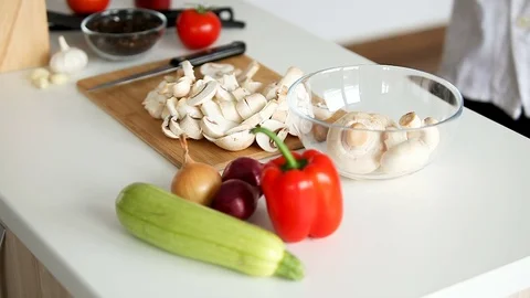 Chef approaches the table and takes the cut mushrooms and puts them in a bowl Stock Footage 85318589